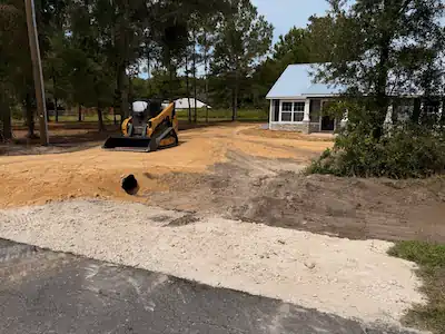 Compact track loader grading a lot beside a new home
